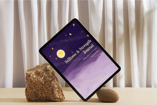 Tablet displaying a 'Stillness & Strength Journal' on a wooden surface with rocks and curtains in the background